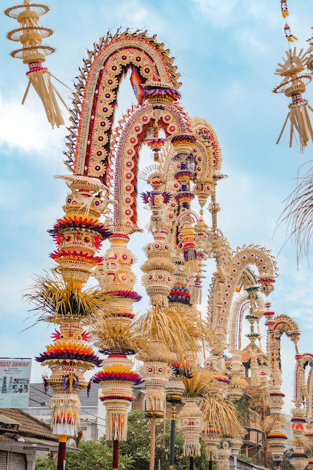 Tall, decorated Balinese ceremonial ornaments and shrine displays against a blue sky.